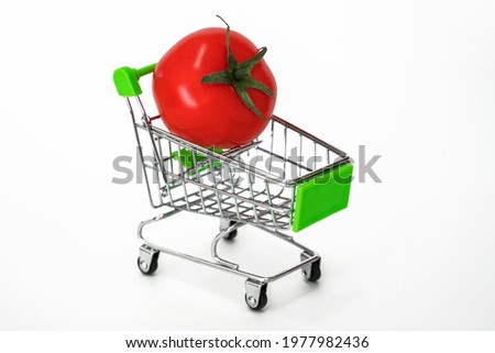 Shopping cart with food products. Ripe red tomato in a grocery cart.  Autumn harvest of vegetables.