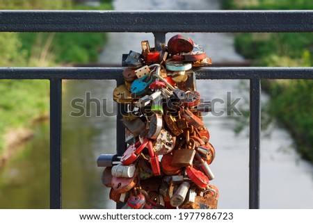 Barn castles, symbol of newlyweds, wedding tradition. Many metal locks are attached to the railing of the bridge over the river in the park during the summer day.
