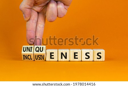 Inclusiveness and uniqueness symbol. Businessman turns wooden cubes, changes words inclusiveness to uniqueness. Beautiful orange background. Business, inclusiveness and uniqueness concept. Copy space.