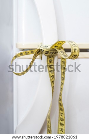 fridge handles tied with a measuring tape, looking like a bow, present concept Royalty-Free Stock Photo #1978021061