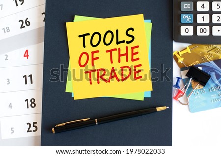 Tools of the trade, text on yellow paper square shape on a blue background. Notepad, calculator, credit cards, pen, stationery on the desktop. Business and education concept. Selective focus.