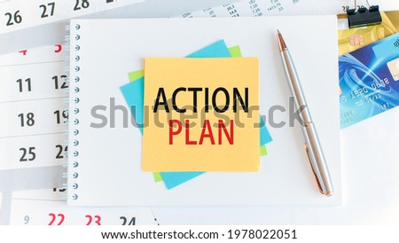 Text action plan written on yellow paper square shape. Credit cards, pen, stationery on the white desktop background. Business, finance and education concept. Selective focus.