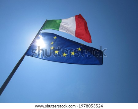 Italian flag with the flag of European Union waving in the wind illuminated by the sun