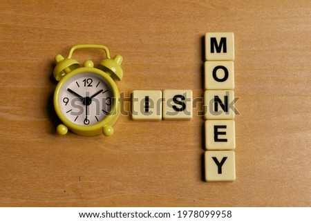 Top view of clock and alphabet letters. Time is money concept.