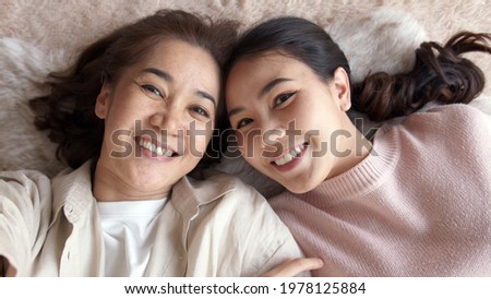 POV attractive beautiful two people asia young lady girl use mobile phone take photo picture video overjoy lying down at home floor have good time day together quarantine in mum healthy health care.