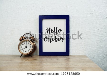 Hello October typography text and alarm clock on wooden table background