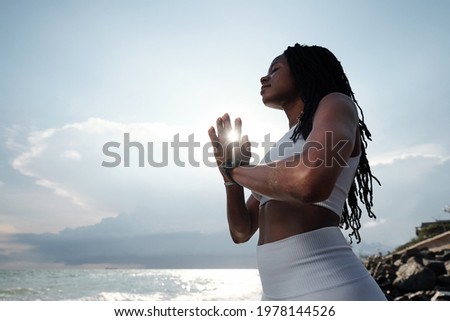 Beautiful calm fit young woman keeping hands in namaste mudra when meditating on sea beach Royalty-Free Stock Photo #1978144526