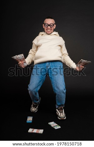 Young happy businessman dancing with a stack of money isolated on black background.