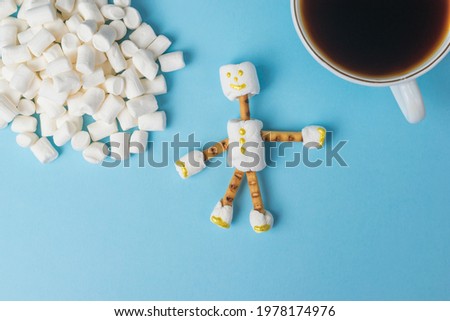Marshmallow, a man and a cup of coffee on a blue background. A collage of sweets. Flat lay.