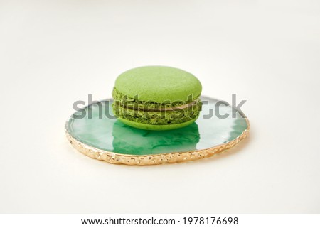 One Green macaroon on original marble green plate on white background, french cookies macarons. Minimal concept. Copy space