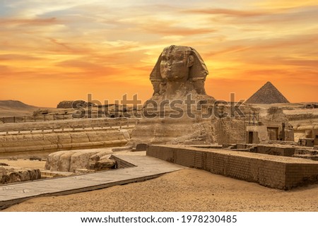 Landscape with Egyptian pyramids, Great Sphinx and silhouettes Ancient symbols and landmarks of Egypt for your travel concept to Africa in golden sunlight. The Sphinx in Giza pyramid complex at sunset Royalty-Free Stock Photo #1978230485