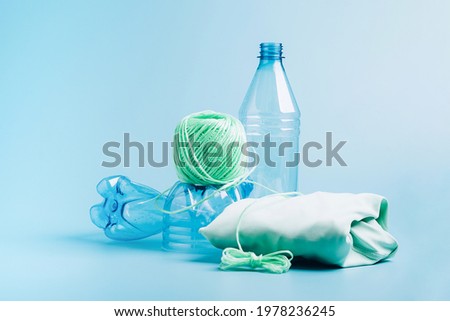 The concept recycling plastic. Empty plastic bottle and recycled polyester fiber, synthetic fabric blue background Royalty-Free Stock Photo #1978236245