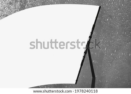 Car windshield wiper cleaning water drops from glass Royalty-Free Stock Photo #1978240118
