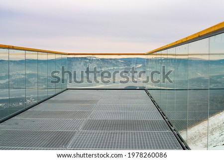 Observation deck with transparent glass railing and wooden railings. Observation deck canopy from the mountainside with mountain views. Royalty-Free Stock Photo #1978260086