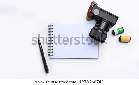 Above view of empty notebook and camera on photographer workspace.