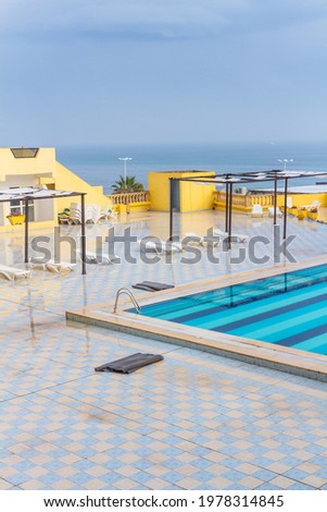Outdoor hotel pool off season. White plastic loungers, empty pool. Resort overlooking the Mediterranean sea in off-season. Tunisia