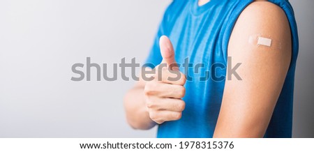 Happy man showing her arm with bandage after receiving vaccine. Vaccination, immunization, inoculation and Coronavirus ( Covid-19 ) pandemic Royalty-Free Stock Photo #1978315376