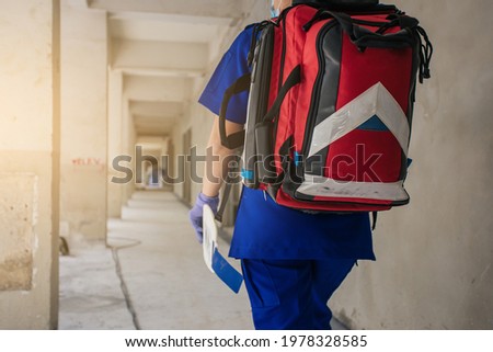 Selective focus first aid bag. Paramedic female walking in construction site work.