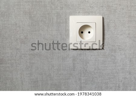 Electrical outlet on the gray wall. Electricity, safety, energy saving concept.