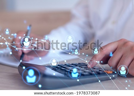 HR specialist researching and analyzing the data of salary on employment market to forecast ongoing expenses of the company using calculator. Hiring new talented officers. Social media hologram icons Royalty-Free Stock Photo #1978373087