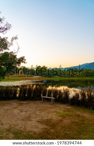 wood bench with beautiful lake at Chiang Mai with forested mountain and twilight sky in Thailand .