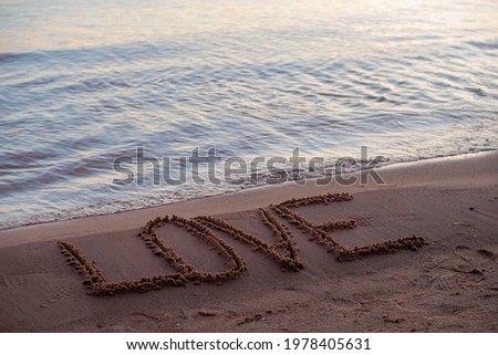 love sign whiten on the sand at the beach. Romantic love symbol at tropical seashore at sunset.