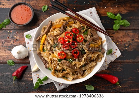 Stir fry Beef Chow Fun with rice noodles, bean sprouts, spring onions and chili. Royalty-Free Stock Photo #1978406336