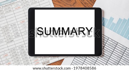 Tablet with text Summary on your desktop with documents, reports and graphs. Business and finance concept
