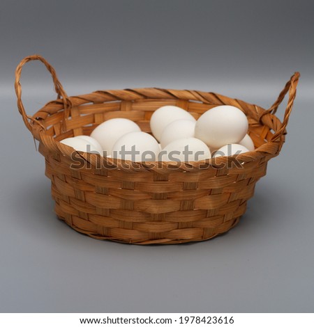 Basket with white chicken eggs on a gray background.