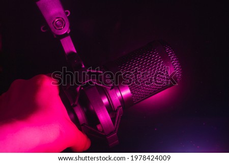 Black microphone for recording sound in the red light in the studio. Copy space.