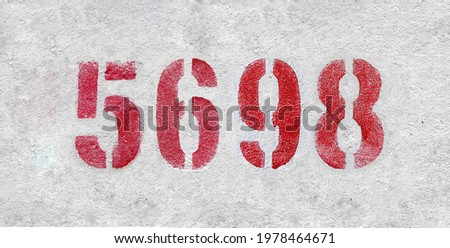 Red Number 5698 on the white wall. Spray paint.