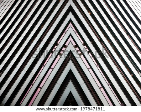 Close-up photo of structural glazing. Wall and windows of modern building. Abstract futuristic hi-tech architecture. Geometric background with triangular pattern of panels and stripes.