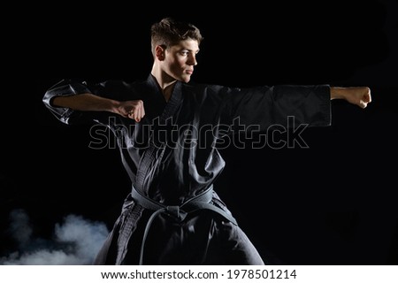 Male karate fighter in black kimono, combat stance