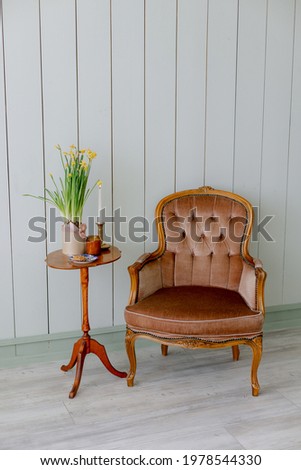 Brown armchair and table with candles flowers on green background