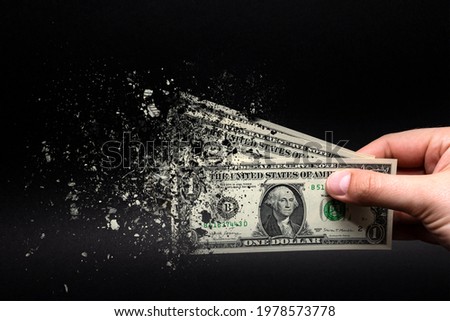 Spend money, spend all your money illiterately. The dollar bill turns to ash, dissolves against a black background. Place for text.