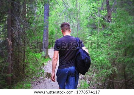 A young man with a backpack travels through the forest. Hiking. Forest trail. Background. Scenery.