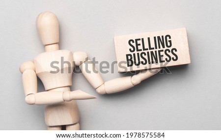 Wooden man shows with a hand to white board with text selling business,concept