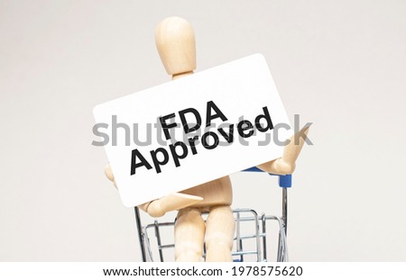 Wooden model of a human in a shopping cart. Grey background. Text fda approved