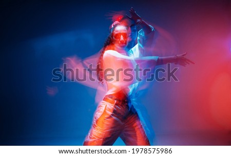 Cool mixed race young girl moving in colourful studio light. Long exposure. Contemporary stylish advertising photo