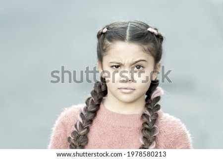 Whats wrong. Little child with puzzled look. Small child wear long brunette braids. Adorable child in casual fashion style. Cute child girl outdoor. Childhood. International childrens day
