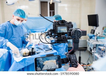 The videographer shoot the surgeon and assistants in the operating room with surgical equipment Royalty-Free Stock Photo #1978590080
