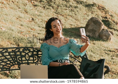 Young woman taking a selfie on a bench of the park lifestyle concept summer style