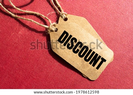 Discount- a paper price tag with a twine against red background, shopping opportunity and consumerism concept