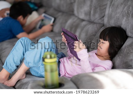 two children addicted tablet, asian kid watching cartoon
