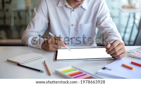 Image businessman designer working on a tablet with a blank white screen with a sample of color at the office. Mock up.