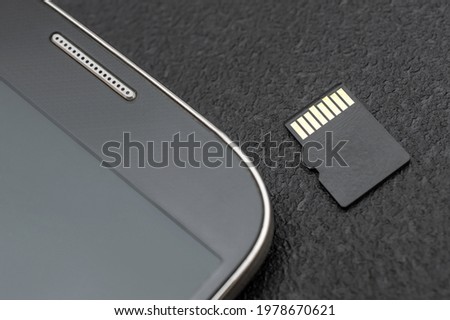 Micro SD memory card with smartphone. Close up.