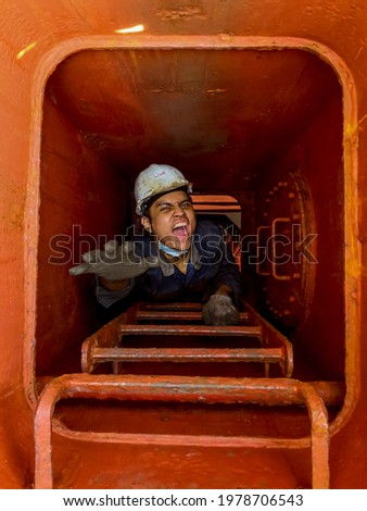 a seaman is climbing a ladder from cargo hold or enclosed space  Royalty-Free Stock Photo #1978706543