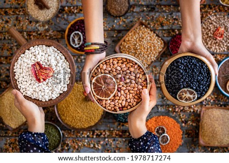 Various of beans at the hands of two women in the bowl. Top view picture of many beans.