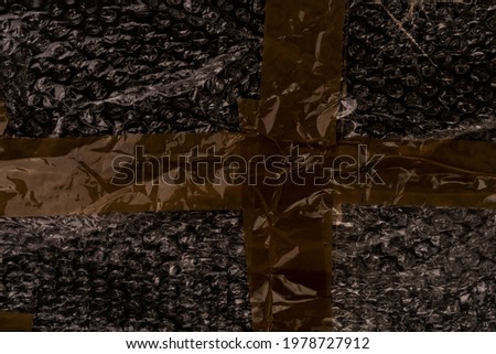 Wrinkled adhesive tape on black bubble wrap. Brown sellotape. Abstract dark background