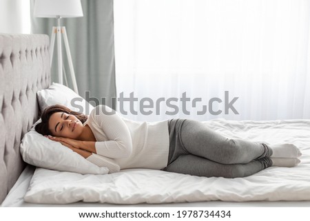 Full body length of calm young black woman sleeping well on the side. Beautiful African American lady resting, enjoying fresh cotton bedding, soft pillow and comfy mattress, banner, free copy space Royalty-Free Stock Photo #1978734434